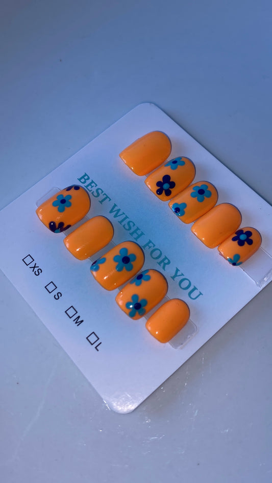 Orange base nails with dark/light blue flowers